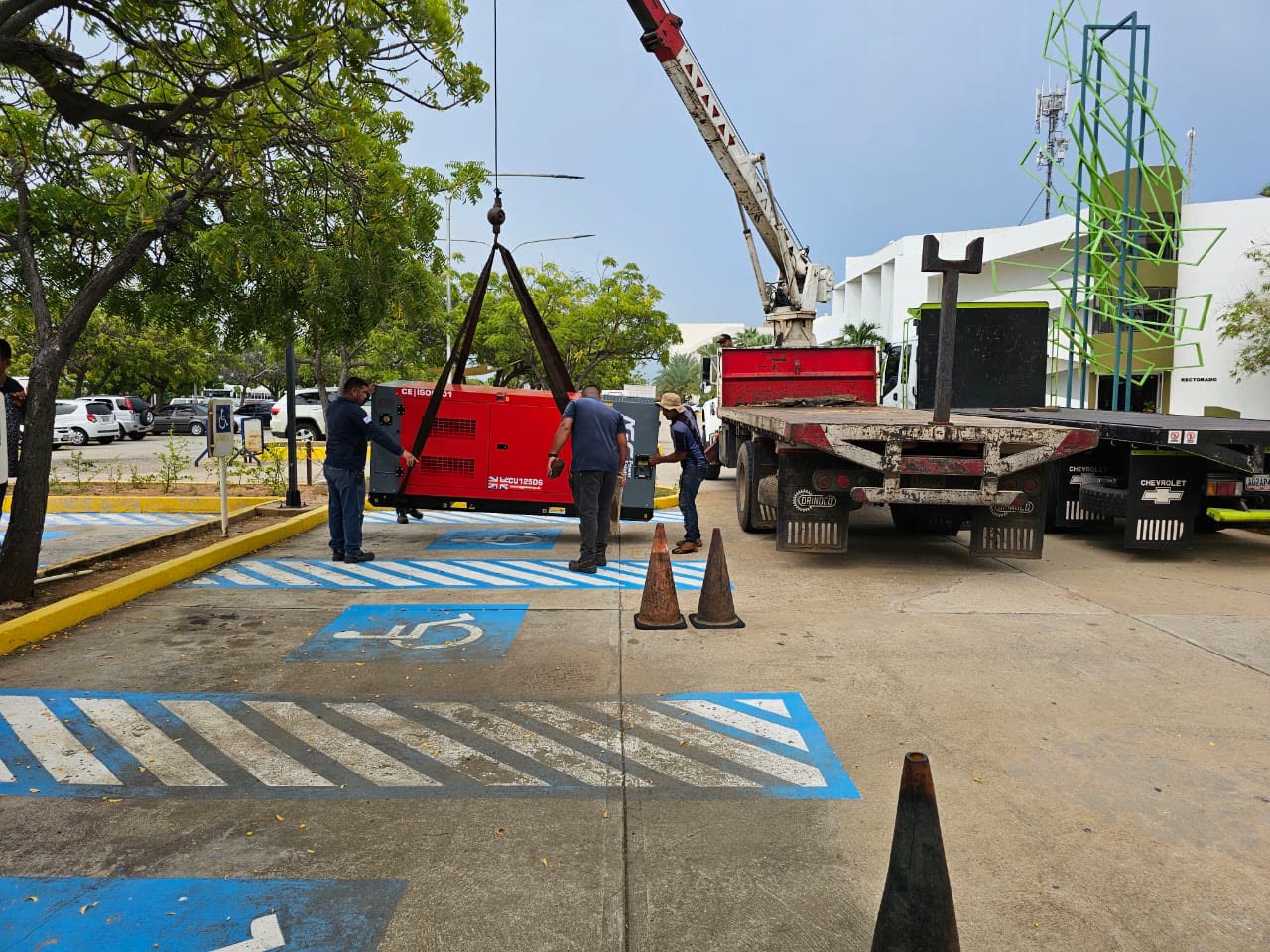 Grúa descargando un generador industrial frente al edificio del Rectorado universitario