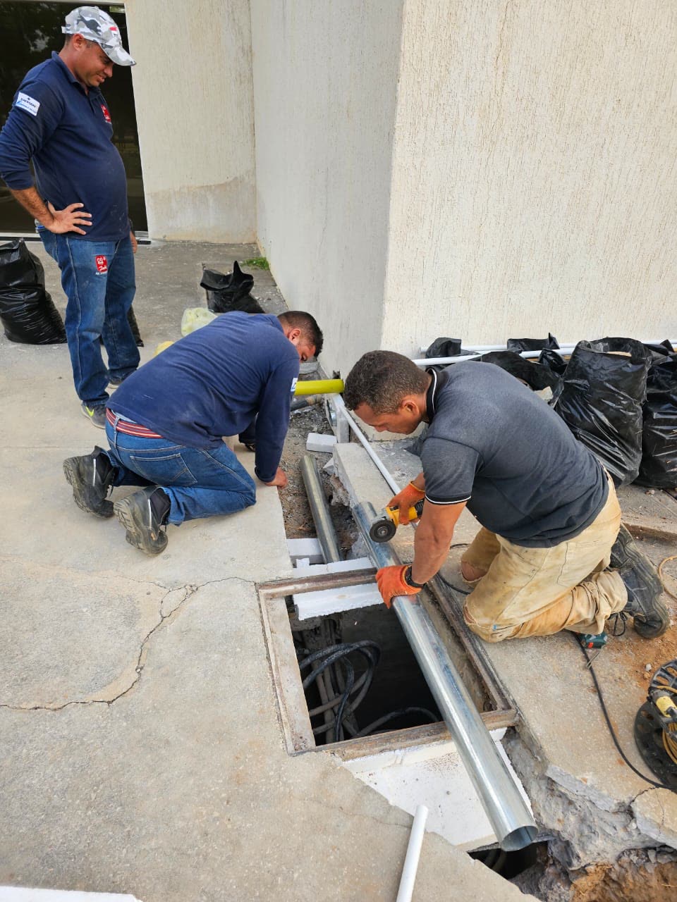 Cuadrilla instalando tubería galvanizada en canalización subterránea