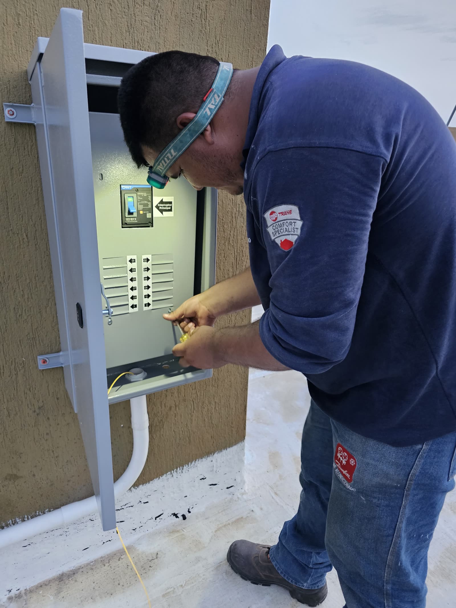 Técnico con linterna frontal cableando un tablero de distribución nuevo con circuitos etiquetados